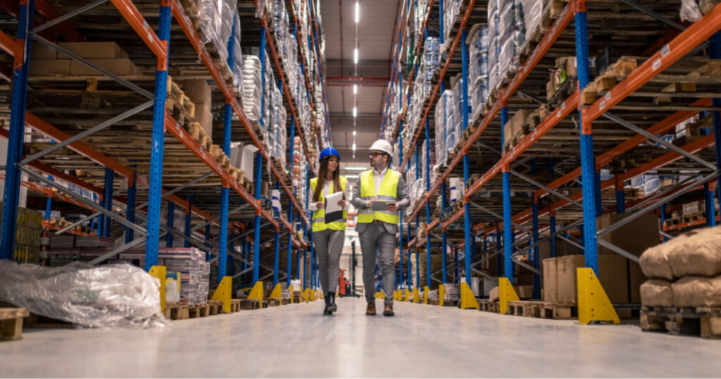 Janitorial technician cleaning a distribution center warehouse floor following OSHA safety protocol